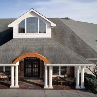 A beautiful house with a large roof, prominent entrance, and columns.