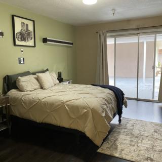 A cozy and minimalist bedroom with a comfortable bed, light green walls, sliding glass doors, and simple decor.
