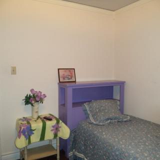 A simple bedroom with a single bed, nightstand, and floral decorations.