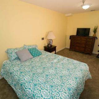 A cozy bedroom with a patterned bedspread and simple furniture.