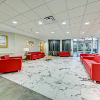 A spacious and modern lobby featuring red sofas and a marble floor.