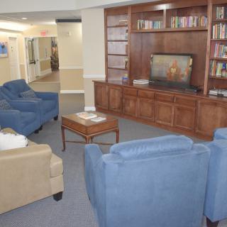 A cozy living room with comfortable seating, a wooden bookshelf, and a television.