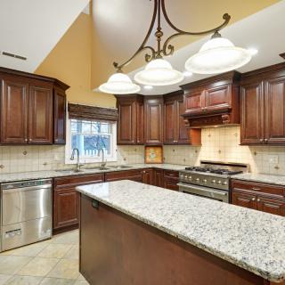 A spacious kitchen with wooden cabinets, a granite island, and modern appliances.