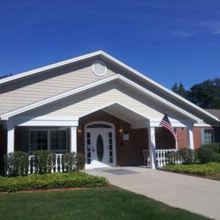 A suburban house with a neatly maintained lawn and a small American flag displayed by the entrance on a sunny day.