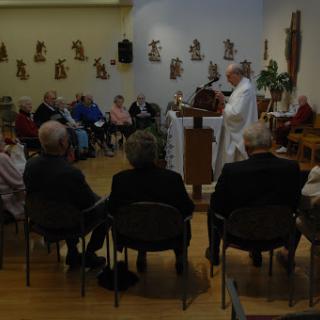 A community gathering during a religious ceremony, with members of the audience attentive to the speaker.