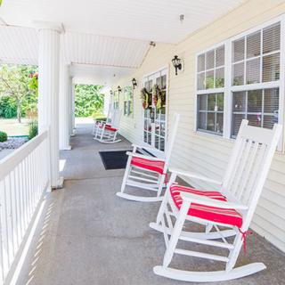 A welcoming porch with white rocking chairs and a view of the garden.