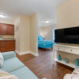 A cozy apartment interior with a view of the living area, television, and bedroom.