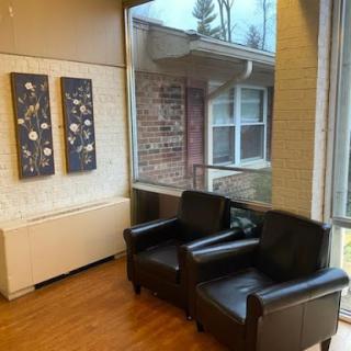 A cozy lounge area featuring black leather chairs and modern artwork.