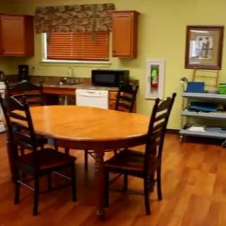 A cozy kitchen with a wooden dining table and chairs, featuring modern appliances and cabinetry.
