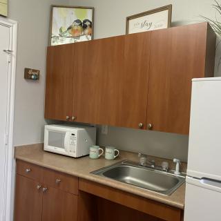 A small kitchen area with a microwave, sink, and wooden cabinets.