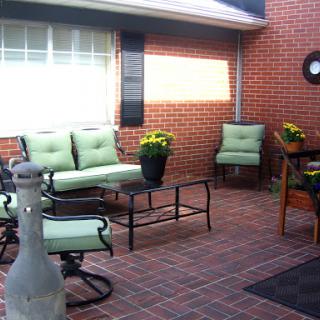 A cozy outdoor patio area featuring comfortable seating and decorative flowers.
