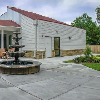 A modern house with a landscaped yard featuring a patio and a fountain.