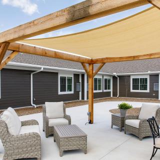 A cozy outdoor patio area featuring wicker furniture and a shade structure.