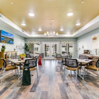 A modern dining room with neatly arranged tables and chairs, featuring elegant lighting and stylish decor.