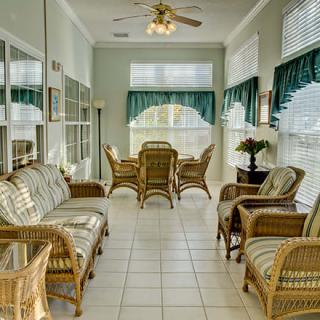 A bright sunroom with wicker furniture and large windows letting in natural light.