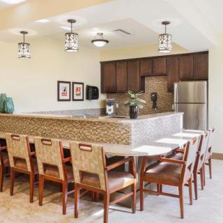 A modern kitchen and dining area with wooden cabinetry, stainless steel appliances, and seating for eight.