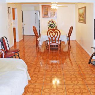 A cozy living room featuring a tiled floor and a dining area with elegant chairs.