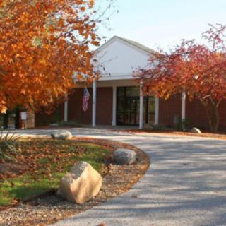 An entrance surrounded by vibrant autumn trees and a winding driveway.