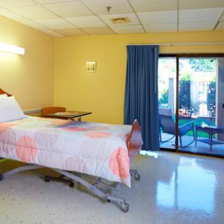 A serene hospital patient room featuring a single bed, curtains, and a view of the outside.