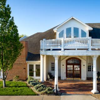 A beautiful two-story house featuring a spacious front porch and balcony.