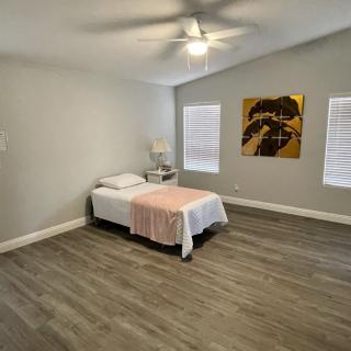 A minimalist bedroom with a single bed, wooden floors, and decorative wall art.