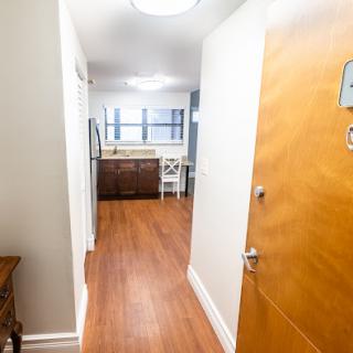A welcoming hallway leading into a spacious apartment with a view of the kitchen.