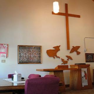 Interior of a church featuring an altar and a cross on the wall.