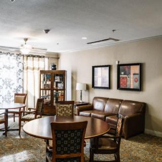 A cozy living room with a sofa, chairs, coffee table, and bookshelf adorned with artwork on the walls.