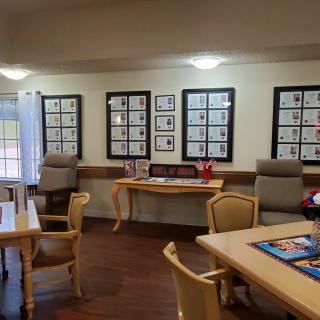 A well-lit room with tables and chairs, decorated with framed artwork on the walls.