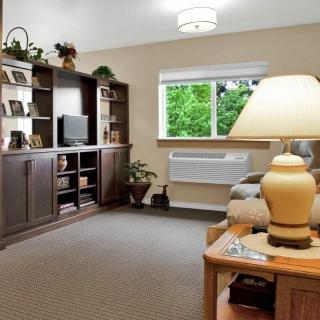 A cozy living room with plush seating, a TV on a wooden entertainment center, and soft lighting from a table lamp.