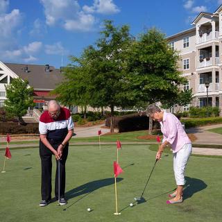 Elderly couple enjoying a game of golf in a residential community.