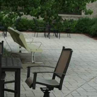 A patio area with chairs and a table surrounded by greenery.