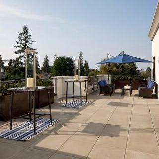 A sunny patio area with tables, chairs, and an umbrella.