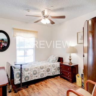 A cozy bedroom with a single bed, wooden furniture, and a ceiling fan.