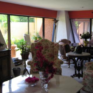 A cozy living room with floral armchairs and large windows overlooking a garden.