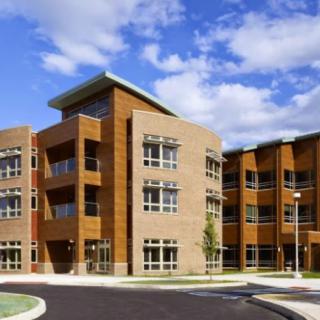 A modern, multi-story school building with a distinctive architectural design under a clear blue sky.