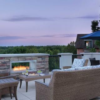 An inviting outdoor patio with a cozy fireplace and comfortable seating, set against a serene evening sky.