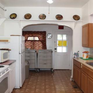 A traditional kitchen with wooden cabinets, a stove, and a microwave, featuring decorative plates on the wall.