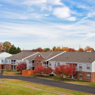 A suburban apartment complex surrounded by colorful autumn trees under a clear blue sky.