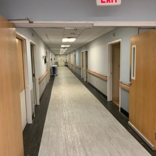 A quiet hospital hallway with doors on either side, leading to patient rooms.