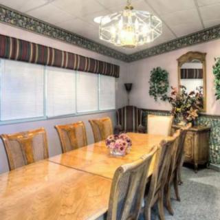 A well-decorated dining room featuring a long wooden table, multiple chairs, and a chandelier.