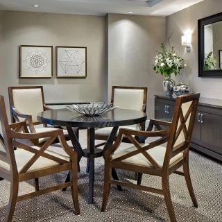 A stylish dining area featuring a round table with four chairs, decorated with artwork on the wall and flowers on a sideboard.