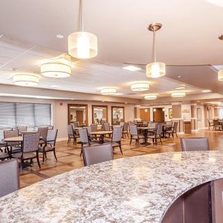 A modern dining area with tables and chairs, illuminated by elegant lighting fixtures.