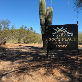 A sign in the desert reads 'Doc's Place - Jeep Rental' with a cactus and hills in the background.