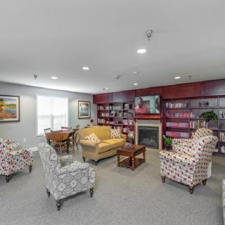 A cozy living room with patterned chairs, a sofa, bookshelves, and a fireplace.