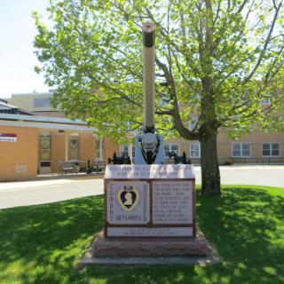 A military memorial dedicated to honoring veterans, featuring a central structure and plaque surrounded by greenery.