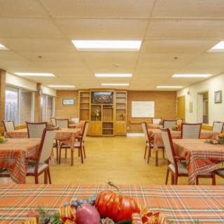 A spacious dining area with tables and chairs neatly arranged, featuring colorful tablecloths and decorative items.