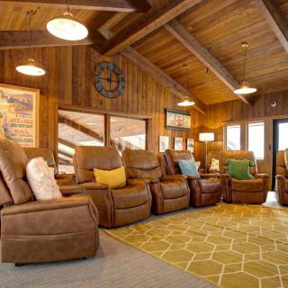 A cozy living room with a wooden interior featuring multiple recliner chairs and warm lighting.