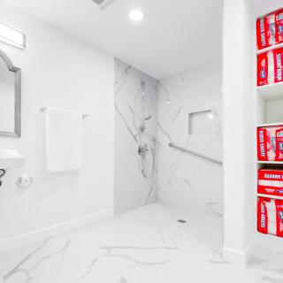 A sleek, modern bathroom with marble tile accents and neatly arranged towels.