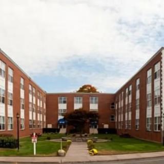 A symmetrical brick building with multiple windows and well-maintained landscaping.